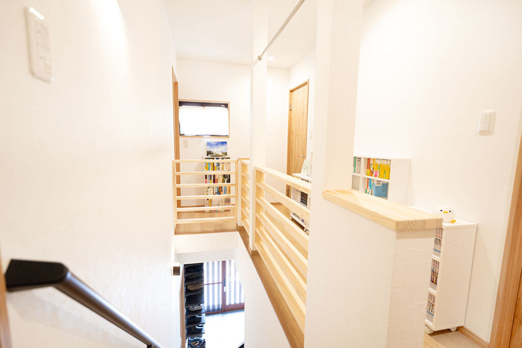 2階廊下には白木の手すりを設置。柱の上部に渡したパイプにはスーツや洗濯物を干せます。>